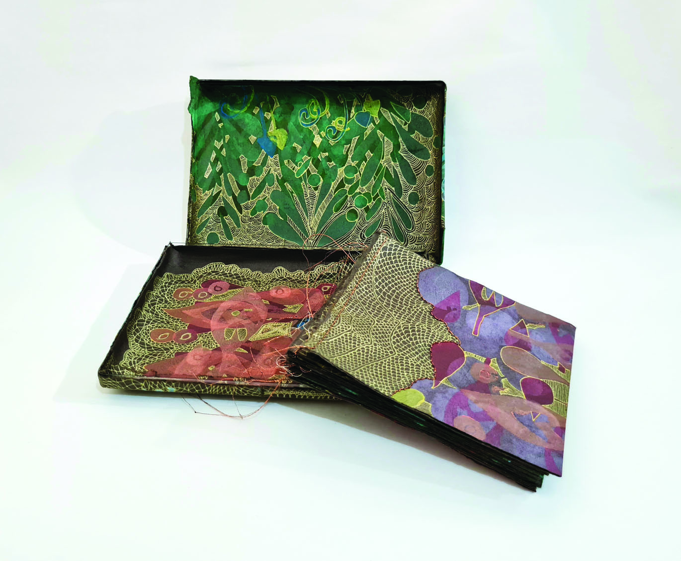 Series of woodblock prints with metallic stitching housed in a container covered in coloured woodblock prints